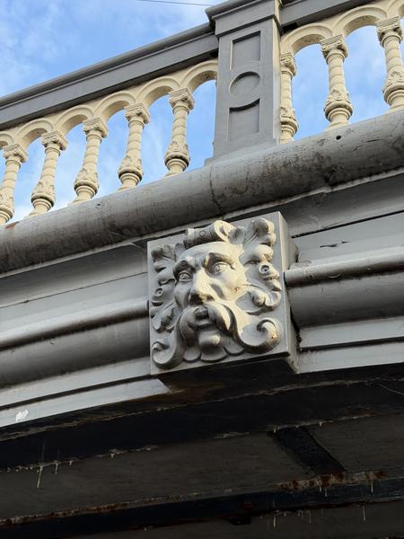 A close-up shot captures the intricate details of the Blauwbrug in Amsterdam, showcasing its ornate balustrade and a decorative stone face sculpture